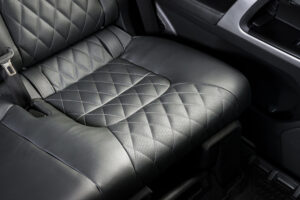 Hands installing car seat covers with hooks under a car seat.