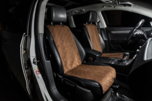 Hands touching heavy-duty car seat cover material on a vehicle seat